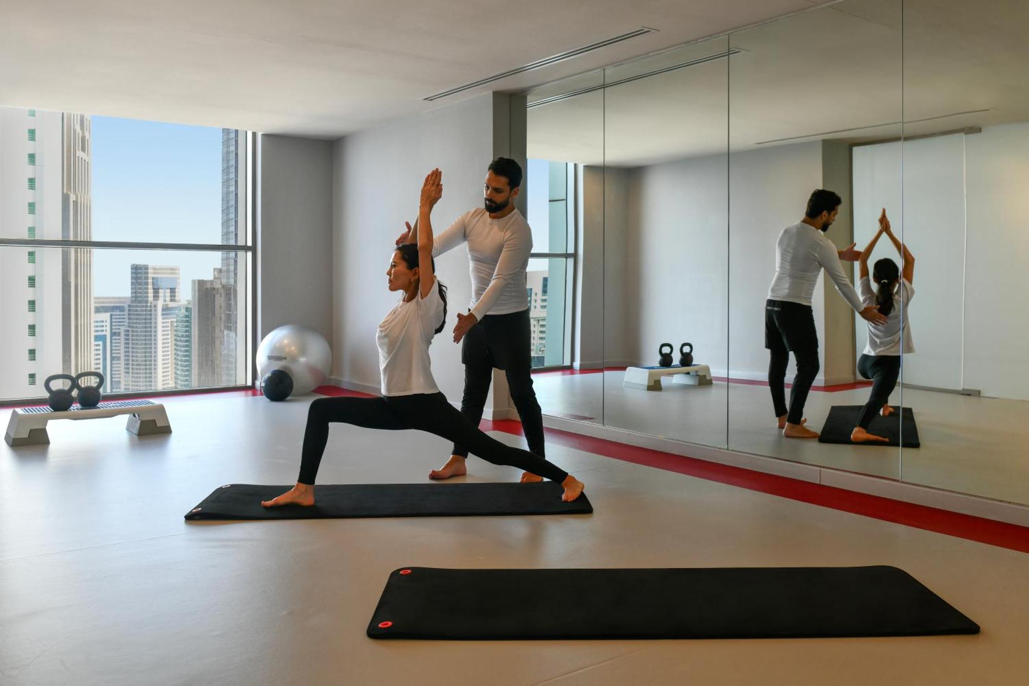 Dusit Doha Hotel Esterno foto A personal trainer assisting a woman with a yoga workout
